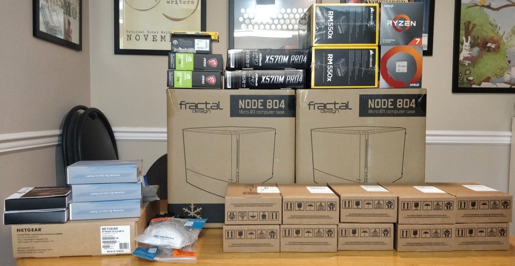 A stack of boxes with computer hardware in them, waiting to be built into a storage cluster, sitting on a dining room table.