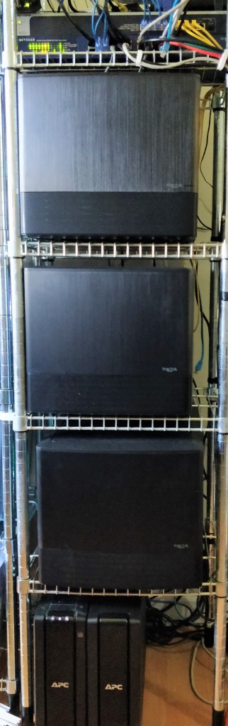 An Ikea Omar rack with three computers as well a UPS at the bottom, two network switches at the top and a bunch of network cabling.